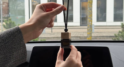 Aromatic 89 glass air freshener hanging from a rear-view mirror
