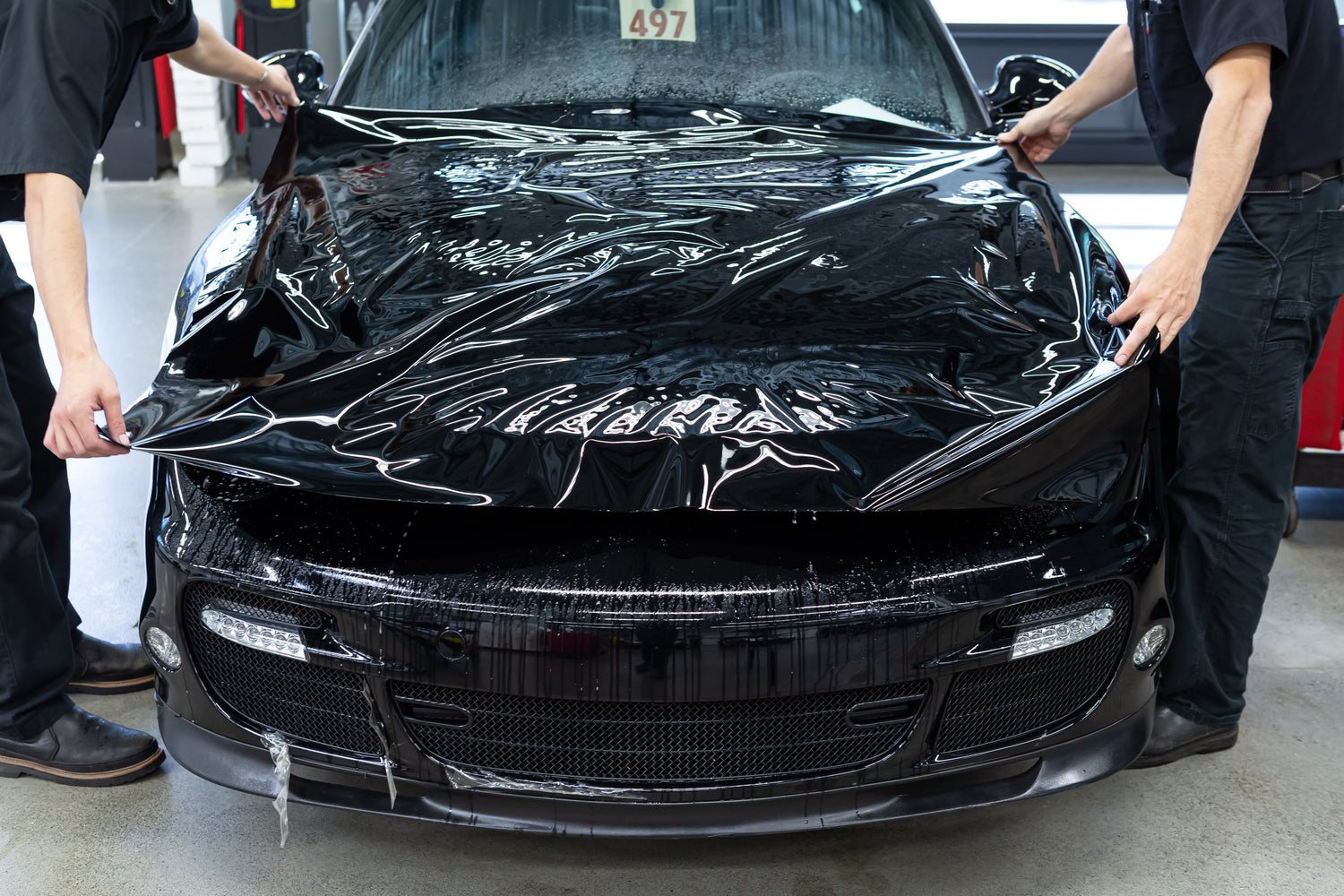 Car being wrapped with black ppf in a garage setting